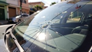 Trinca pequena no para-brisa de carro sob luz solar, risco de aumento